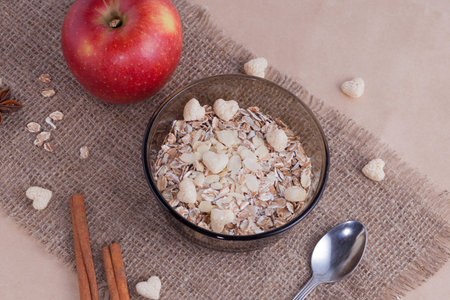 Healthy food. Muesli in a bowl on a light background with a red delicious apple. Breakfast porridge...