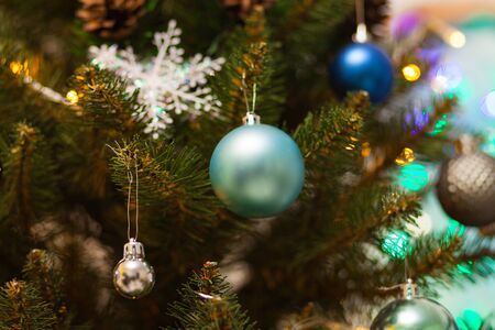 Beautiful green Christmas tree decorated with blue balls and garlands. Close-up photo. Sparkling backgroundの写真素材