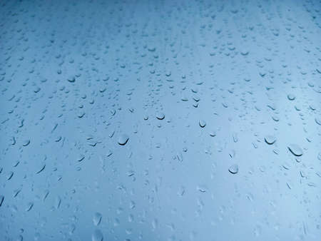 Raindrops on a window pane close-up. Abstract blue background.の写真素材