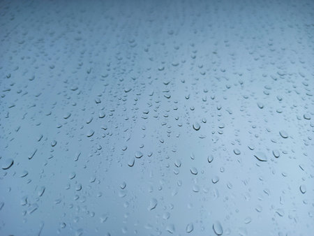 Raindrops on a window pane close-up. Abstract blue background.の写真素材