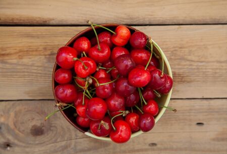 ripe red sweet cherry in a bowl on a wooden tableの写真素材