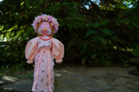 handmade motanka doll of pink color on a green background of flowers