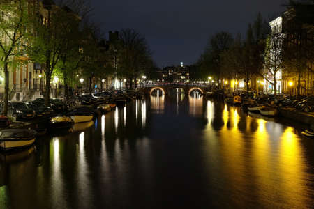 Amsterdam buildings and canal with reflections on water at night backgroundのeditorial素材