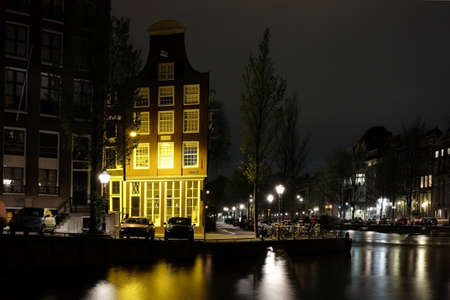Night in Amsterdam: illuminated building near the river canal with reflection on waterのeditorial素材
