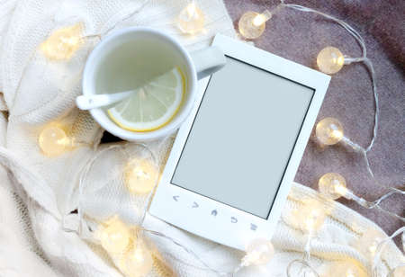 Ebook, cup and electric garland on textile background with free copy spaceの写真素材