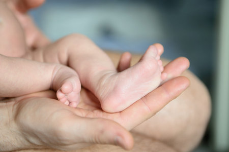 Childrens feet in hands of father.