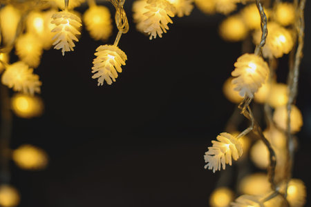 Blurred yellow christmas lights in shape of cones on dark background, low depth of focus.