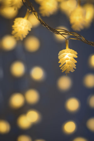 Blurred yellow christmas lights in shape of cones on dark background, low depth of focus with copyspace. Vertical view.の写真素材