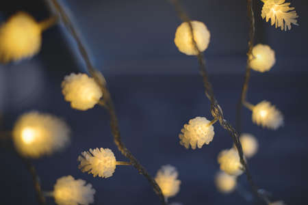 Blurred yellow christmas lights in shape of cones on dark background, low depth of focus.の写真素材