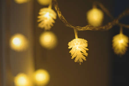 Blurred yellow christmas lights in shape of cones on dark background, low depth of focus.の写真素材