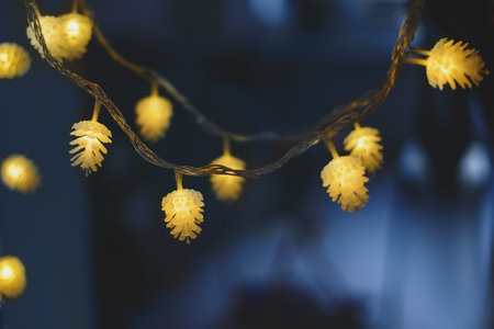 Blurred yellow christmas lights in shape of cones on dark background, low depth of focus.の写真素材