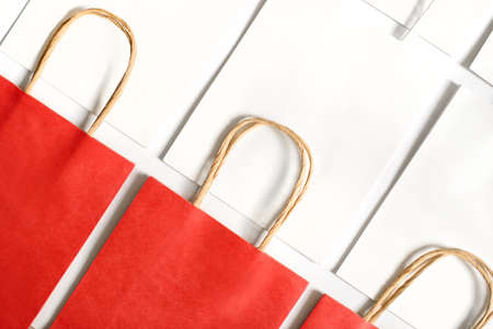 One red shopping bag in background of white bags isolated on white background. Black friday or Christmas sales.の写真素材