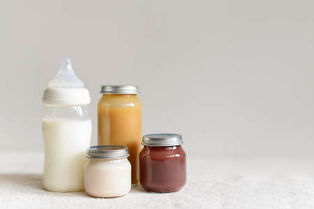 Bottles of milk and puree for baby over blurred background with free copy spaceの写真素材