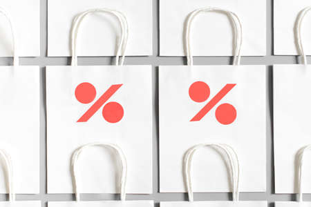 White shopping bags from recycle paper with percent sign on gray background. Black friday or Christmas sales.の写真素材