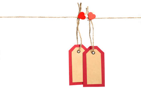 Two red and brown paper tags hanging on the rope by heart shape pin with copy space isolated on white background. St.Valentines gift concept.の写真素材