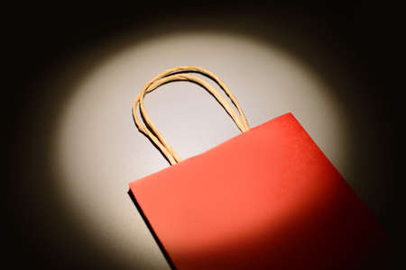 Red shopping bag in the ray of scenic spot light over dark background.の写真素材