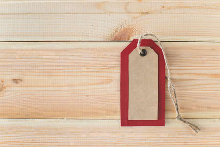Recycled craft paper red tag and rope on vintage wooden table background with free copy space. Top view. Mock up sample.の写真素材