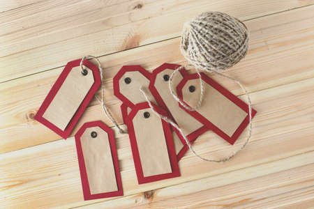 Recycled craft paper red tags and rope on vintage wooden table background. Top view. Mock up sample.の写真素材