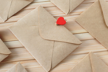 Envelope from craft paper with red heart pins on the wooden background.の写真素材