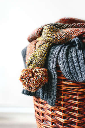 Stack of knitted winter scarfs on straw basket isolated on white background.の写真素材