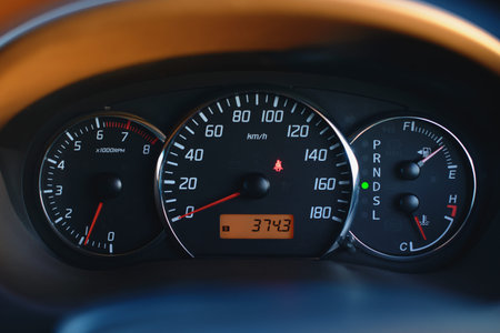 Car dashboard with speedometer and tachometer in black color, close up.