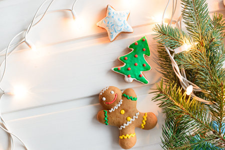 Christmas cookies with festive decoration and christmas lights on white wooden background. New Year...