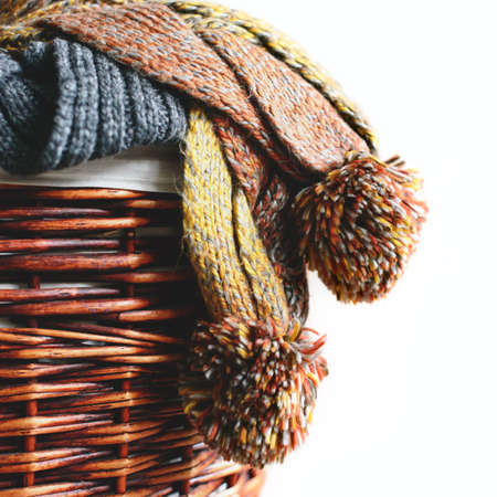 Stack of knitted winter scarfs on straw basket isolated on white background.の写真素材