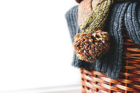 Pile of knitted winter scarfs on straw basket isolated on white background. Free copy space.