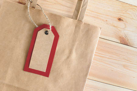 Recycled craft paper envelope, red paper bag and tags on vintage wooden table background. Top view. Mock up sample.の写真素材