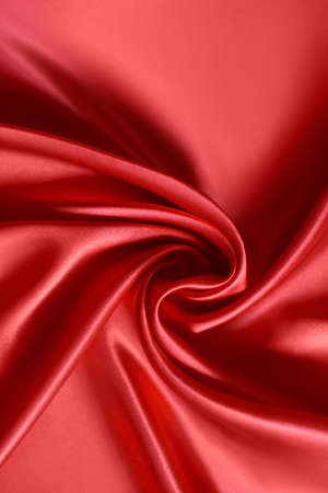 Close up of ripplesin shape of rose flower in red silk fabric. Satin textile background.の写真素材