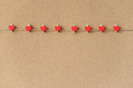 Red hearts shape pins garland over brown craft recycle cork board background. Free copy space....