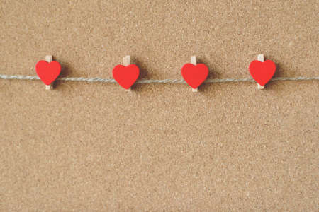 Red hearts shape pins garland over brown craft recycle cork board background. Free copy space. Valentine's day concept.の写真素材