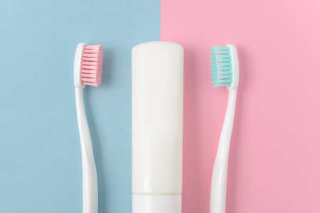Close up of two plastic white toothbrushes with pink and blue bristle and toothpaste on pink and blue background. Free copy space.の写真素材