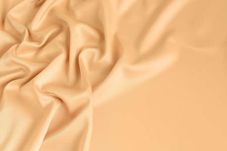 Close up of ripples in gold colored silk fabric. Satin textile background. Free copy space.の写真素材
