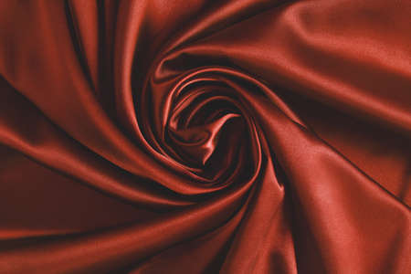 Close up of ripplesin shape of rose flower in red silk fabric. Satin textile background.の写真素材