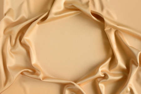 Close up of ripples in gold colored silk fabric in shape of frame. Satin textile background. Free copy space.の写真素材