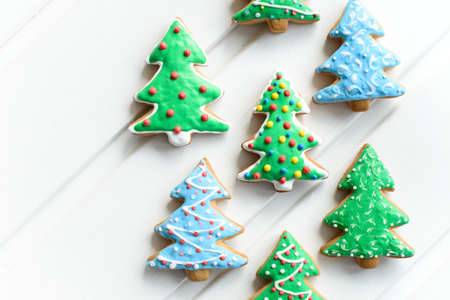 Christmas cookies in shape of fir-tree with festive decoration on white wooden background. New Year and Christmas concept. Free copy space.の写真素材
