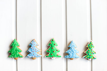 Christmas cookies in shape of fir-tree with festive decoration on white wooden background. New Year and Christmas concept. Free copy space.の写真素材