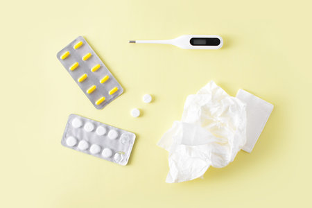Pills, napkins for the nose and thermometer on yellow background. Cold and flu treatment set. Flat...