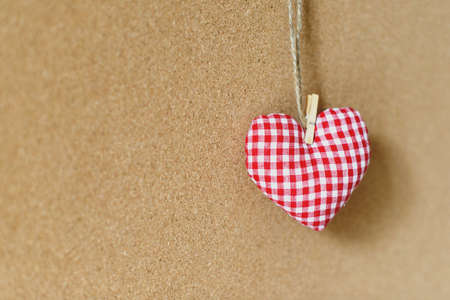 Red textile heart over brown craft recycle cork board background. Free copy space. Valentine's day concept.の写真素材