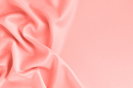 Close up of ripples on silk fabric. Satin textile background. Living Coral color. Color of the year 2019. Free copy space.の写真素材
