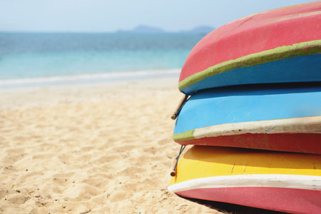 Kayaks stacked on sand beach. Colorful boats in front of sea coast. Vacation and travel sport...