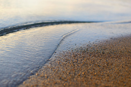 Sea wave and sand seashore. Golden sun light over the sea ocean waves. MIrror reflection on water surface. Macro close up.の写真素材