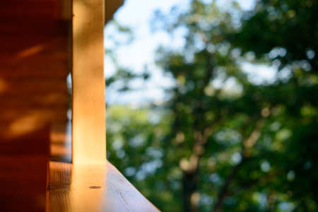 View of forest and trees from a wooden balcony. Wooden balcony nature view of summer forest. Blurred background, free copy space.の写真素材