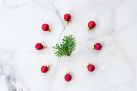 Stylized Christmas clock made of fir-tree branch and red ball toys on marble background. New Year and Christmas celebration concept. Flat lay, top view.の写真素材