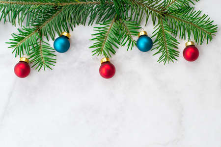 Fir-tree branches decorated with red and blue balls on gray marble background. New Year, Christmas and winter concept. Flat lay, top view, free copy space.の写真素材