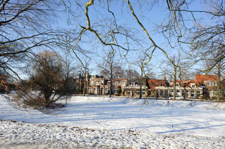 Frozen water and show on canal and traditional old brick buildings with tile roofs at sunny winter day in Hoorn city, Holland Kroon, Netherlands.の写真素材