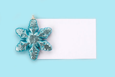 White paper card decorated with snowflakes on light blue background. New Year, Christmas and winter...