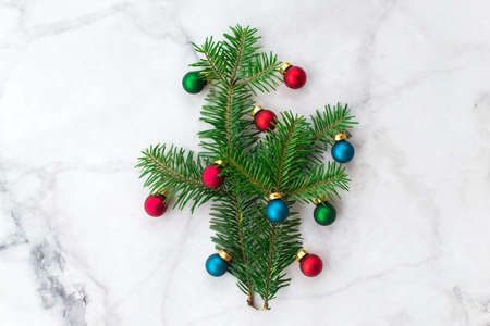 Fir-tree branches decorated with red and blue balls on gray marble background. New Year, Christmas and winter concept. Flat lay, top view, free copy space.の写真素材