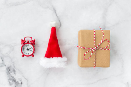 Christmas gift wrapped in brown craft paper and Christmas toys on gray marble background. New Year,...